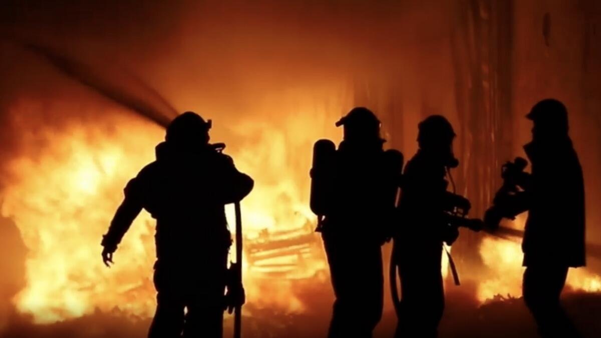 Thick black smoke rises from a 14-story shopping mall in Zigong, Sichuan province, China, as emergency workers respond to the fire