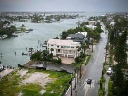 A flooded street in a southern US city due to Tropical Storm Debby, showing submerged cars and homes |whispergaze