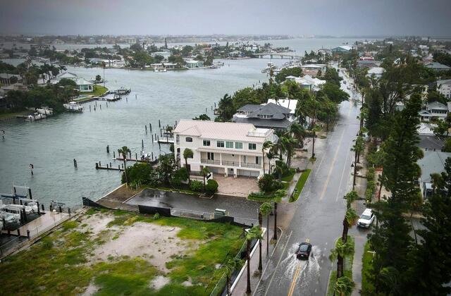 A flooded street in a southern US city due to Tropical Storm Debby, showing submerged cars and homes |whispergaze